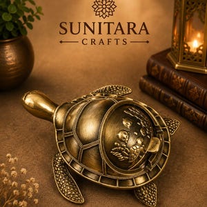 May include: A brass-coloured metal turtle figurine with a hinged shell that opens to reveal a compartment. The shell features an embossed design of smaller turtles and aquatic elements. The text SUNITARA CRAFTS is visible above the turtle.