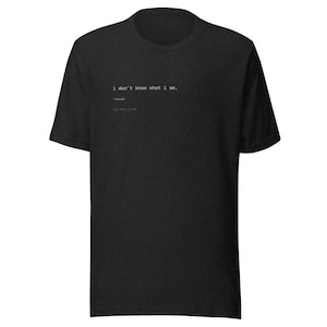 May include: A charcoal grey short-sleeve t-shirt featuring white text printed on the chest that reads: i don't know what i am. -Claude. this game is real. The shirt has a crew neckline and a standard fit, made from a heathered fabric texture.