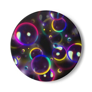 Pode incluir: Um botão circular com fundo preto e um padrão de bolhas translúcidas e iridescentes em tons de rosa, amarelo, azul e roxo. As bolhas variam em tamanho e exibem reflexos de luz, criando um efeito colorido e brilhante na superfície do objeto.