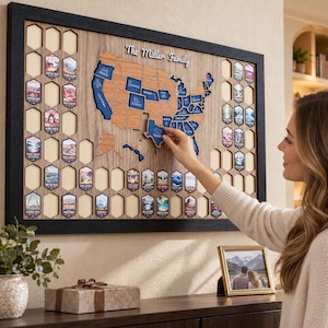 May include: A framed wooden map of the United States featuring the text The Miller Family, with blue state-shaped cutouts and hexagonal slots for national park tokens. A hand places a blue Texas-shaped piece into the map board.