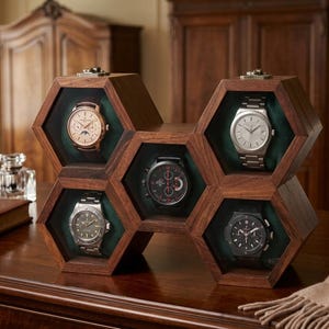 May include: A dark wood watch display case featuring five hexagonal compartments arranged in a honeycomb pattern. Each compartment has a green velvet interior and holds a wristwatch with a unique dial, including silver, black, and rose gold tones.