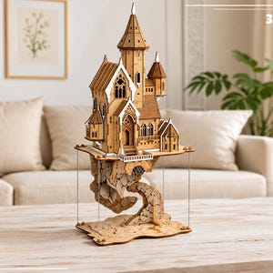 May include: A laser-cut wooden model of a fantasy castle perched on a floating rock formation. The structure features intricate architectural details, including pointed roofs, arched windows, and a central tower. The text 3MM is visible.
