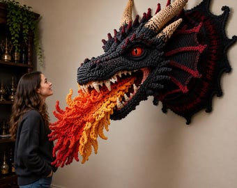 May include: A large, wall-mounted crochet dragon head sculpture in black and dark red, featuring textured scales, beige horns, and a bright orange and yellow crocheted flame emerging from its open mouth with sharp white teeth and glowing red eyes.