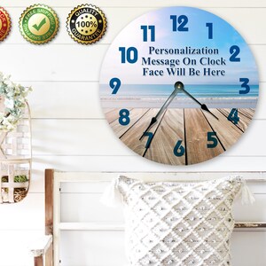 a wall clock with a beach scene as the background, and there are three badges on the wall above it.