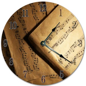 Peut inclure: Horloge murale ronde sur le thème de la musique. Le cadran de l'horloge présente un fond en papier vintage avec des notes de musique et un design classique des aiguilles de l'horloge. Les chiffres sont en police serif. Les aiguilles de l'horloge sont noires.