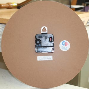 a clock with a brown background, a black clock face, and a white label with text.