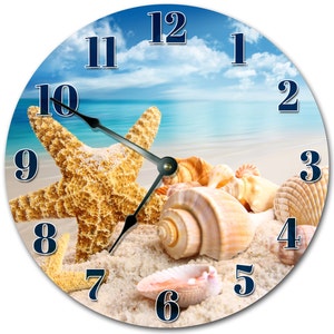 May include: A round clock with a beach scene featuring a starfish, seashells, and blue sky with white clouds. The clock face has blue numbers and black hands.