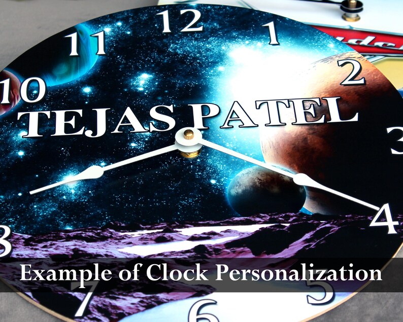 A clock with a space-themed design, featuring planets, stars, and a planet-like object. The text "TEJASPATEL" is prominently displayed on the clock face.