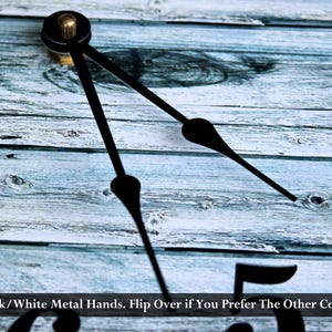 a close-up view of a clock face with black metal hands, set against a wooden background.