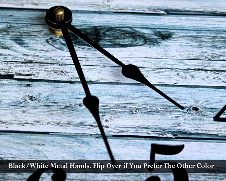 a close-up view of a clock face with black metal hands, set against a wooden background.