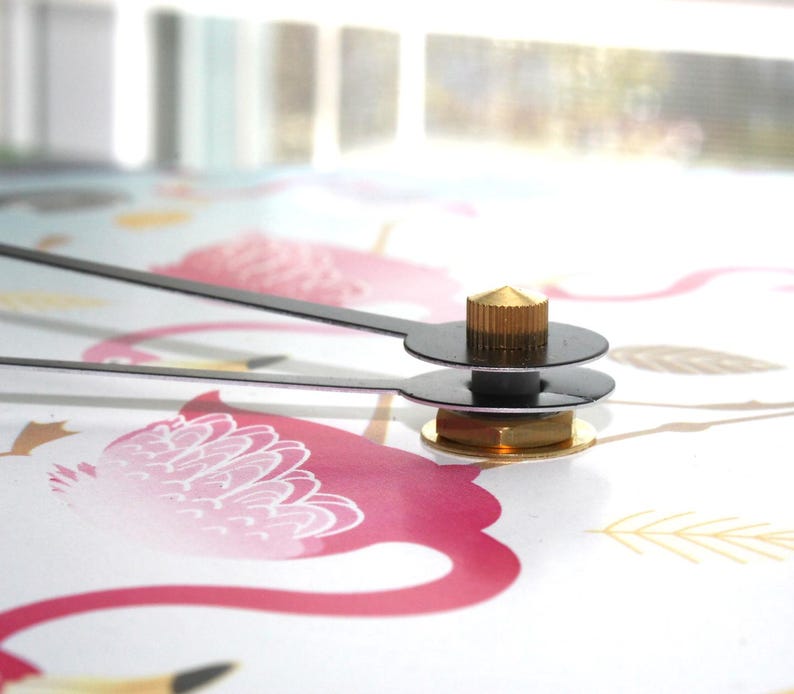 a close-up view of a clock mechanism with a pink and white floral pattern on the surface it is mounted on.