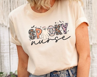 Może przedstawiać: Kremowa koszulka z nadrukiem graficznym, który głosi "Spooky Nurse" w kolorowych literach w stylu patchworku z duchem w środku słowa "Spooky".
