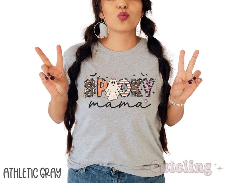 May include: A gray t-shirt with the text "Spooky mama" in colorful letters with a ghost and other Halloween-themed designs.