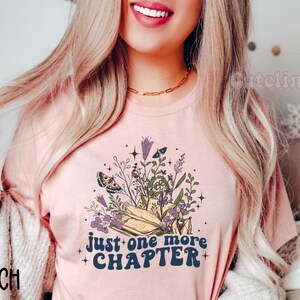 Puede incluir: Una camiseta rosa con un dise&ntilde;o floral y el texto "just one more chapter" en una fuente retro.