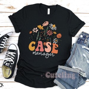 May include: Black t-shirt with a floral design and the text "Case Manager" in a retro font.