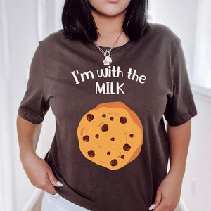 May include: A brown t-shirt with the text "I'm with the MILK" and a chocolate chip cookie graphic.