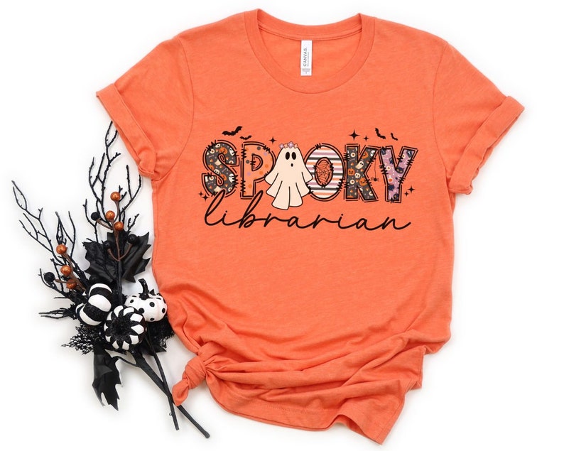 May include: Orange short-sleeved t-shirt with a graphic design of a ghost and the text "Spooky Librarian" in a patchwork style.