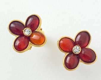May include: A pair of gold tone flower-shaped earrings with red and orange enamel and a clear rhinestone in the center.