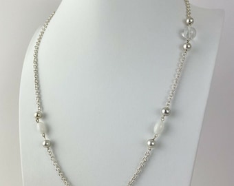 May include: A silver chain necklace with white and clear round beads. The necklace is displayed on a white mannequin.