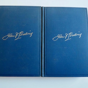 May include: Two hardcover books with navy blue covers. The title "John J. Pershing" is inscribed in gold script on each book. The books are side-by-side, suggesting a set or a pair of volumes.