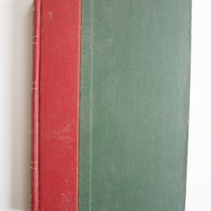 May include: A hardback book with a red spine and a green cover. The spine is red with gold lettering. The cover is a muted green colour. The book is closed and appears to be in good condition.