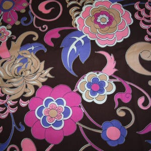 May include: A dark brown fabric featuring a repeating floral pattern with stylized flowers in shades of hot pink, light purple, and tan. The design includes swirling vines and leaves in blue and pink, creating a dense, colorful botanical print.