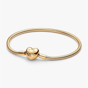 May include: A gold-toned snake chain bracelet featuring a heart-shaped clasp. The clasp is engraved with the text PANDORA. The bracelet has a smooth, flexible, and rounded link design that forms a continuous circular loop when the clasp is closed.