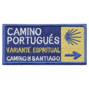 May include: A rectangular embroidered patch featuring a blue background with white text reading CAMINO PORTUGUÉS, VARIANTE ESPIRITUAL, and CAMINO DE SANTIAGO. The right side has a yellow section with a blue scallop shell icon and a blue arrow pointing right.
