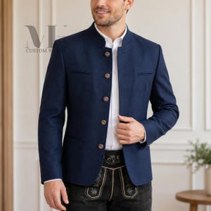 Puede incluir: Una chaqueta azul marino con cuello mao, mangas largas y cinco botones metálicos redondos en la parte delantera. La prenda se lleva sobre una camisa blanca de cuello y pantalones negros con detalles bordados. El texto MH CUSTOM WEARS es visible.