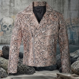 Peut inclure: Une veste de moto avec un motif peau de serpent beige et marron, ornée de clous métalliques argentés sur les épaules et les revers. La veste comprend une fermeture éclair asymétrique, des poches zippées et une doublure intérieure noire.