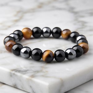 May include: A beaded bracelet featuring a repeating pattern of polished round beads in black, metallic silver, and golden-brown tiger eye. The beads are strung together in a circular arrangement, showcasing a smooth, reflective surface on each individual bead.