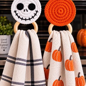 Peut inclure: Deux essuie-mains suspendus avec des anneaux en bois. L'un présente un haut en crochet blanc en forme de crâne avec des yeux noirs et une bouche cousue, associé à un torchon à carreaux noir et blanc. L'autre a un haut en crochet orange.