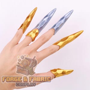 Puede incluir: Un conjunto de cinco piezas de armadura para dedos puntiagudas con una textura geométrica facetada. Tres piezas tienen un acabado dorado metálico, mientras que dos tienen un acabado plateado metálico. El logo de Forge & Fabric Cosplay es visible.