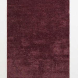 Flat lay of a burgundy wine red plush area rug showing soft shag texture and solid deep red color, ideal for living rooms, bedrooms, or dining rooms, photographed on a plain white background to highlight the rug's plush pile and rich tone.