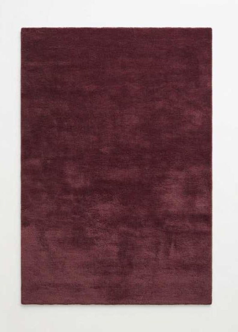 Flat lay of a burgundy wine red plush area rug showing soft shag texture and solid deep red color, ideal for living rooms, bedrooms, or dining rooms, photographed on a plain white background to highlight the rug's plush pile and rich tone.