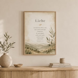 Könnte beinhalten: Ein gerahmtes Wandbild mit einer Aquarell-Landschaft aus sanften Hügeln und Olivenzweigen. Der Text lautet: Liebe, Gott liebt diese Welt so sehr, dass er seinen Sohn gab. Damit jeder, der an ihn glaubt, nicht verloren gehe, sondern ewiges Leben findet. Johannes 3, 16.