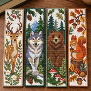May include: Four rectangular cross-stitch bookmarks featuring nature themes. The first shows a deer with berries, the second a wolf in a forest, the third a brown bear with mushrooms, and the fourth a squirrel with acorns and autumn leaves.
