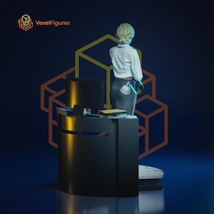 May include: A figurine of a person with short blonde hair wearing a white collared shirt and a dark skirt, standing behind a black desk with a computer monitor and a small lamp. The text VoxelFigures appears in the top left corner of the image.
