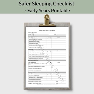 Op de afbeelding: Een wit papieren document getiteld Safer Sleeping Checklist - Early Years Printable, bevestigd aan een grijs houten klembord met een gouden metalen clip. De checklist bevat secties voor slaapomgeving, positionering, toezicht en veiligheid.