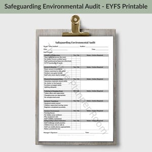 May include: A white paper document titled Safeguarding Environmental Audit - EYFS Printable, secured on a wooden clipboard with a gold metal clip. The form contains sections for visibility, security, environment, and safety checklists with blank fields.