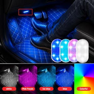 May include: An oval-shaped LED car interior light with a textured surface, shown in white, blue, pink, and ice blue. The light is installed in a vehicle footwell with blue diamond-stitched floor mats and metal pedals, illuminating the car floor.