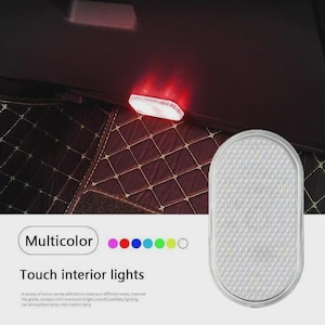 May include: An oval-shaped, white touch-activated interior light with a textured, grid-patterned surface. The device emits a red glow in the upper portion of the image. Text on the image reads "Multicolor" and "Touch interior lights."