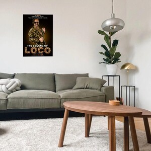 May include: A living room scene featuring a poster for "The Legend of Loco" movie. The poster shows a man in sunglasses and a leopard print jacket. A gray sofa, wooden coffee table, and a modern lamp are also visible.