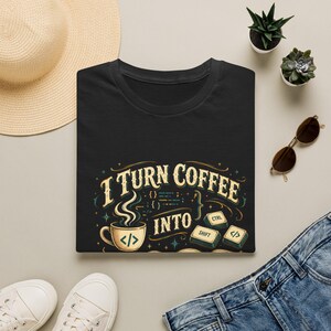 May include: A black t-shirt featuring a graphic with the text I TURN COFFEE INTO, a steaming coffee cup with a code symbol, and computer keyboard keys labeled CTRL, SHIFT, and a code symbol, all rendered in a vintage cream and teal color palette.
