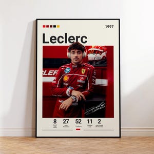 Könnte beinhalten: Ein gerahmtes Poster mit einem Porträt von Charles Leclerc im roten Rennanzug mit Kopfhörern vor rotem Hintergrund. Der Text enthält Leclerc, 1997, sowie Statistiken zu Grand-Prix-Siegen, Pole-Positions, Podiumsplätzen und schnellsten Runden.