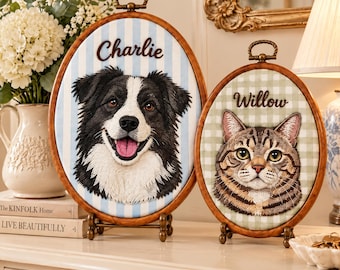 May include: Two oval wooden embroidery hoops on stands featuring stitched portraits. The larger hoop displays a black and white dog with the name Charlie. The smaller hoop displays a brown tabby cat with the name Willow on a green checkered background.