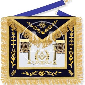 Puede incluir: Un delantal masónico cuadrado con un panel central blanco con columnas bordadas en oro, un símbolo de escuadra y compás con la letra G, y un borde de terciopelo azul con flecos dorados, bordados en oro y una correa ajustable azul.