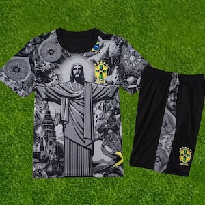 May include: A black and white short-sleeved t-shirt and matching shorts set featuring a graphic print of Christ the Redeemer, intricate patterns, and the yellow and green Brazil national football team crest on both the shirt and shorts.