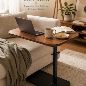 May include: A height-adjustable side table with a dark wood-grain top and a black metal base. The table features the text Comfort Wherever You Need It and A Versatile Side Table for Everyday Living. It holds a laptop, a ceramic mug, and a small plate.