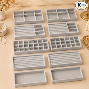 May include: A set of ten rectangular light gray velvet jewelry organizer trays with various internal compartment configurations, including open sections, ring slots, and grid dividers, arranged in a grid pattern on a light surface.